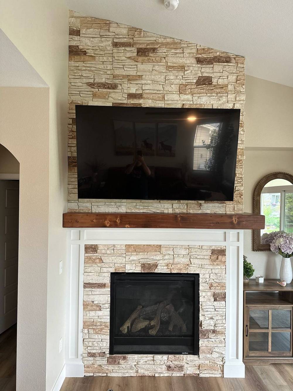 Reclaimed beam mantel floating above a stone fireplace