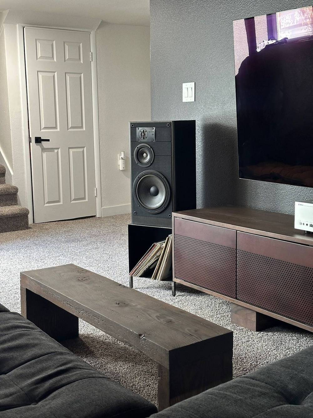 Reclaimed beam used as a media shelf below a mounted television