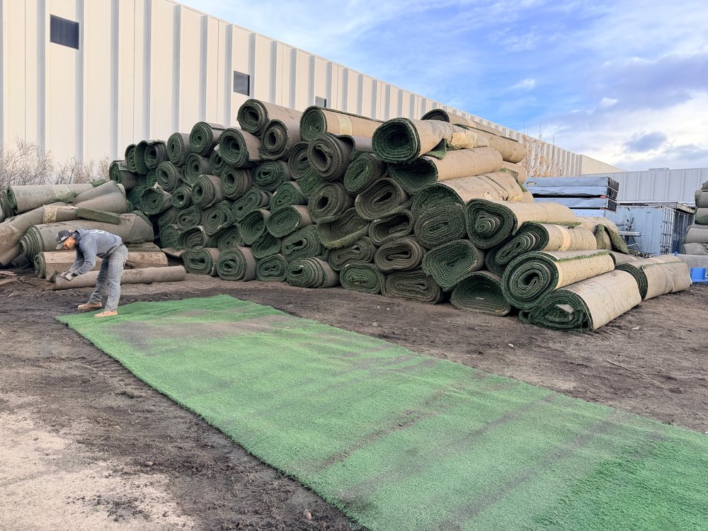 Rolls of retired athletic turf stacked several high in the yard