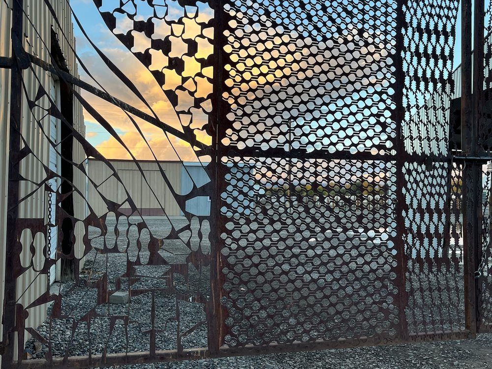 Steel cutout sheets set into a frame as an outdoor screen, punched shapes silhouetted against the sky