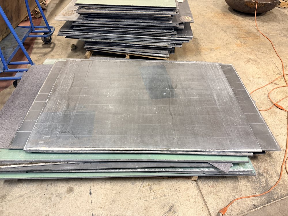 Reclaimed slate chalkboard pieces stacked flat on a rack, dark faces and grey edges
