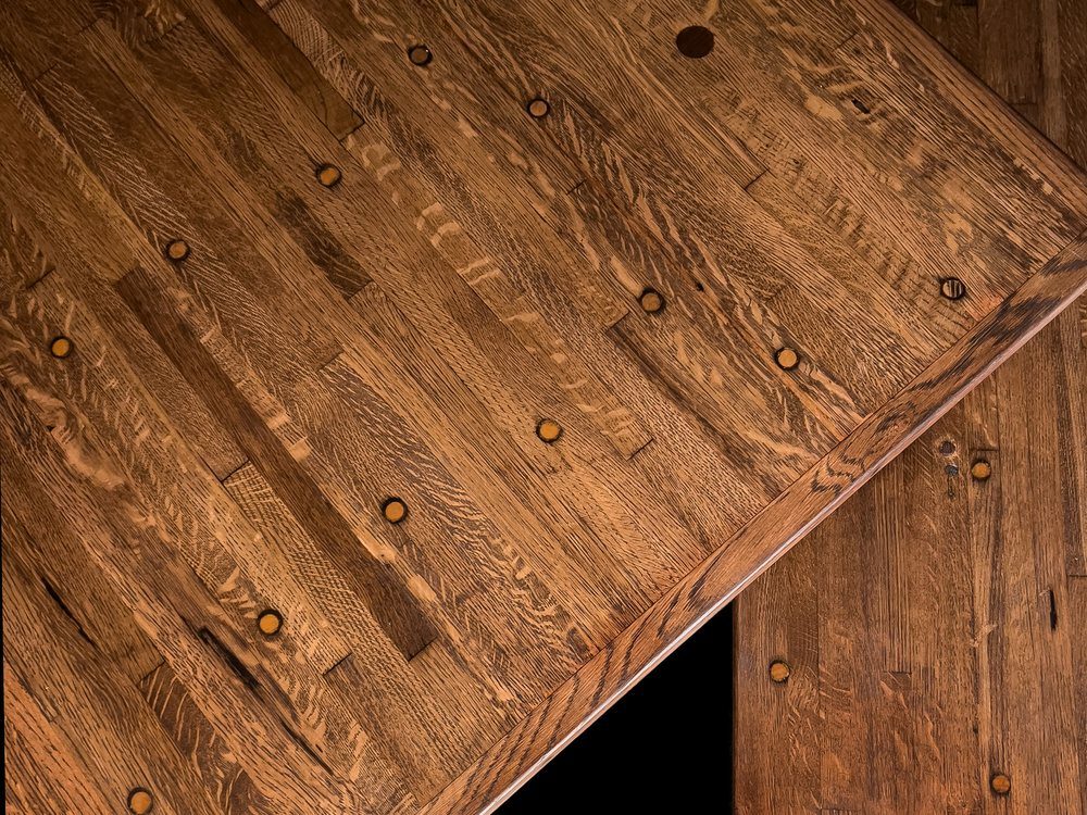 Corner detail of a reclaimed cargo flooring counter top showing knots and plugged bolt holes