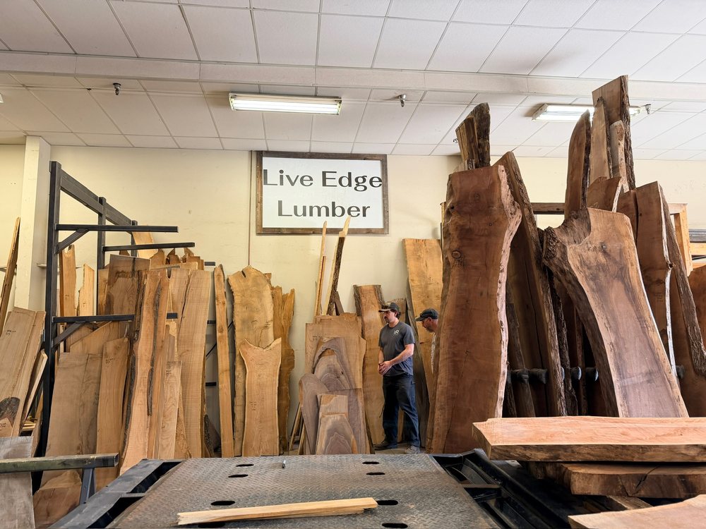 Racks of live edge lumber standing on end under the Live Edge Lumber sign in the Denver yard