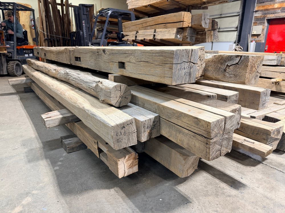 Stack of reclaimed red and white oak beams in the Denver shop, ends toward camera
