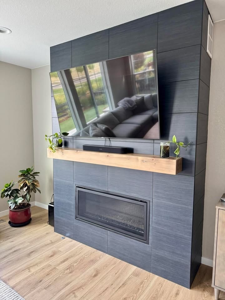 Finished reclaimed fir mantel installed across a tiled fireplace surround, television above and a linear firebox below