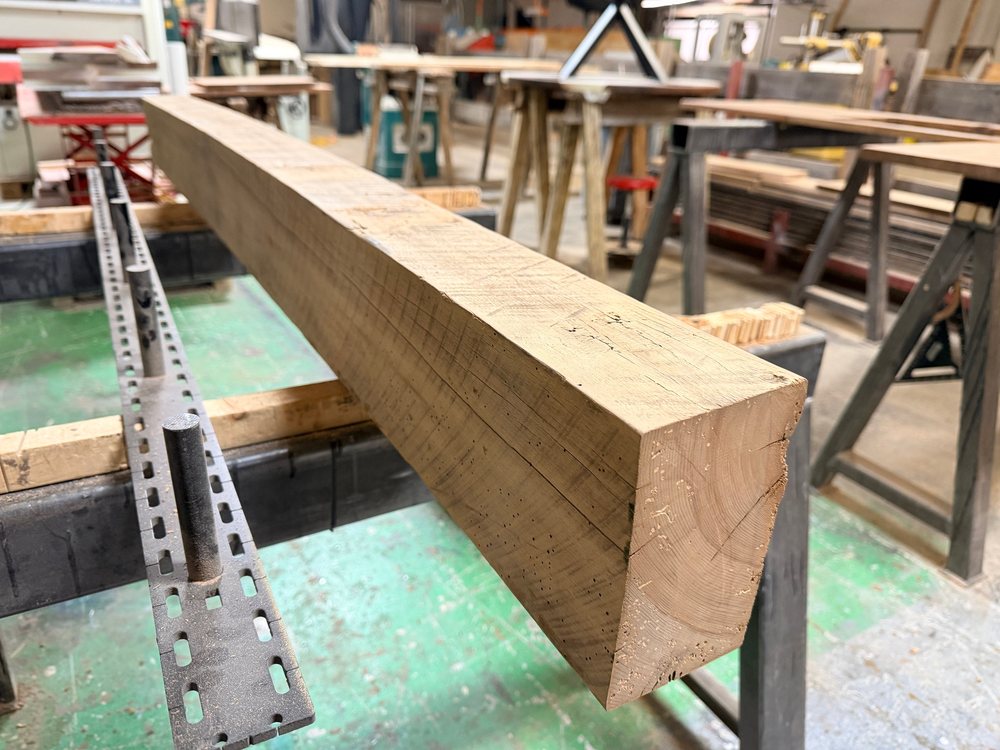 Raw sawn reclaimed beam clamped on the bench, mill marks and rough ends still on it