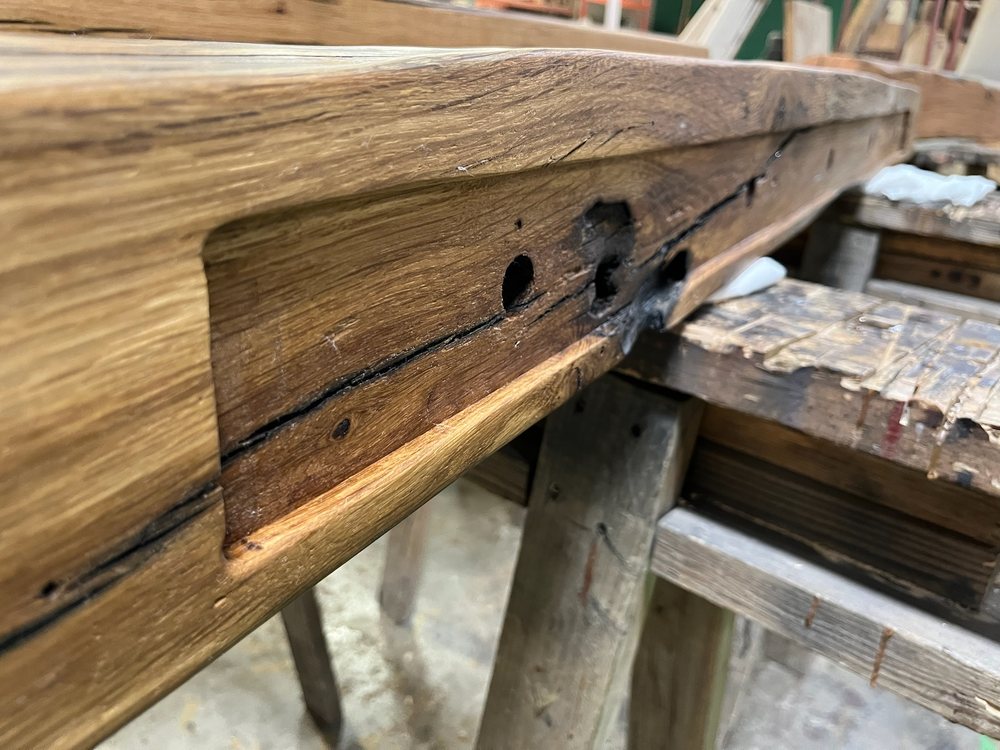 Reclaimed beam sitting on an Ultrashelf steel bracket rail, the hardware visible before it goes into the wall