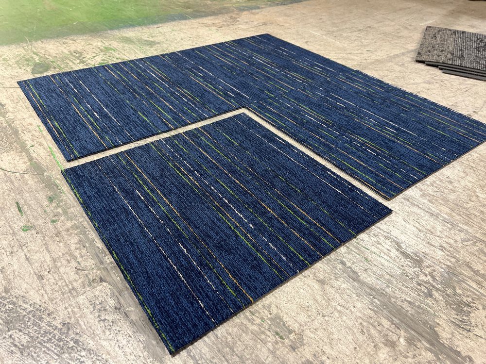 Navy commercial carpet tiles laid out on the warehouse floor