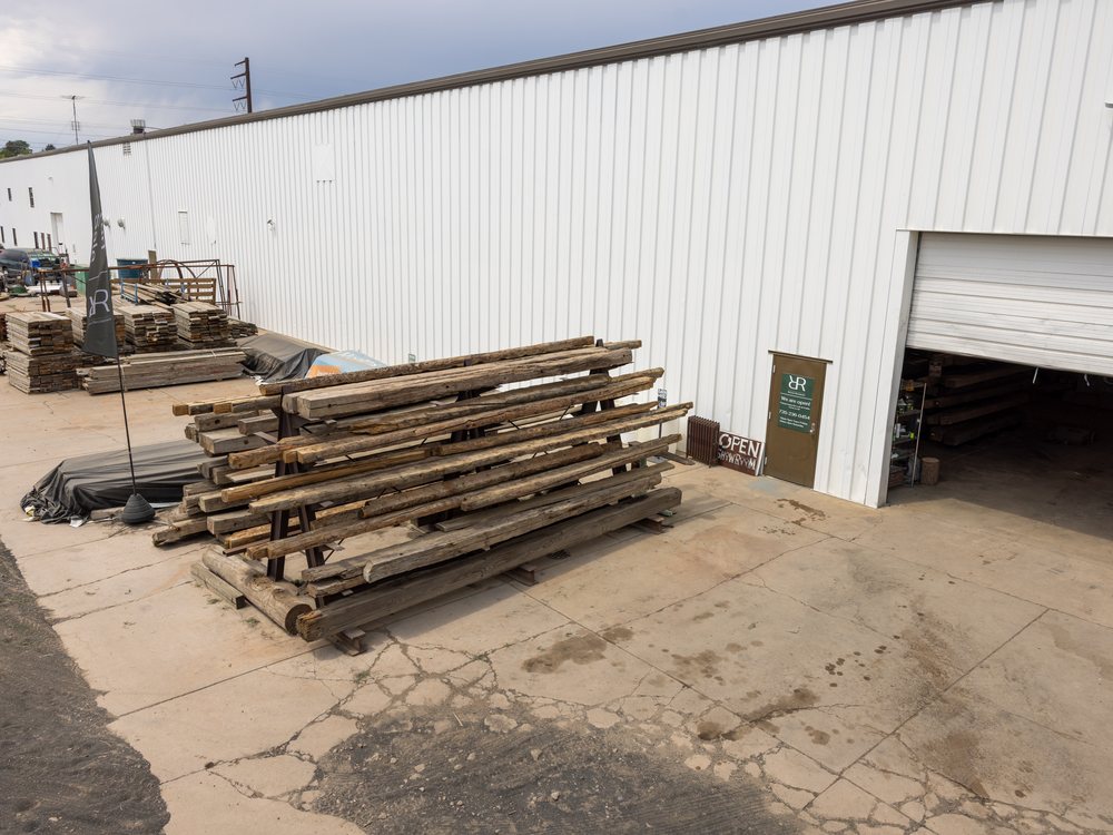 Reclaimed timber stacked outside the roll-up door at 800 S Jason St