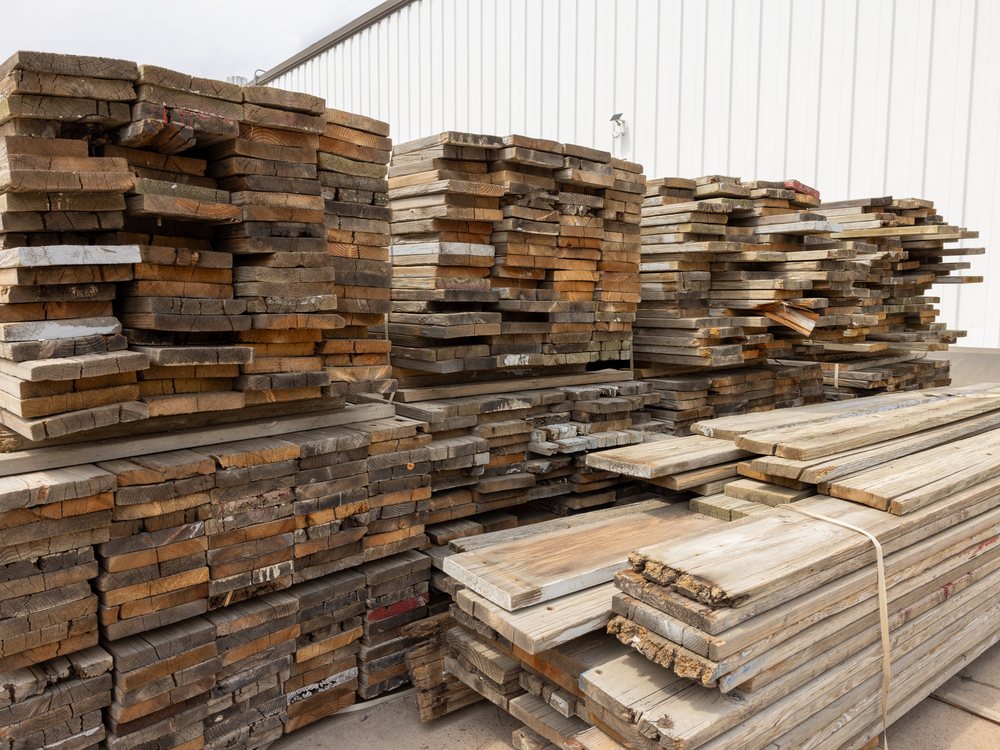 Bundles of reclaimed boards stacked several feet high in the yard