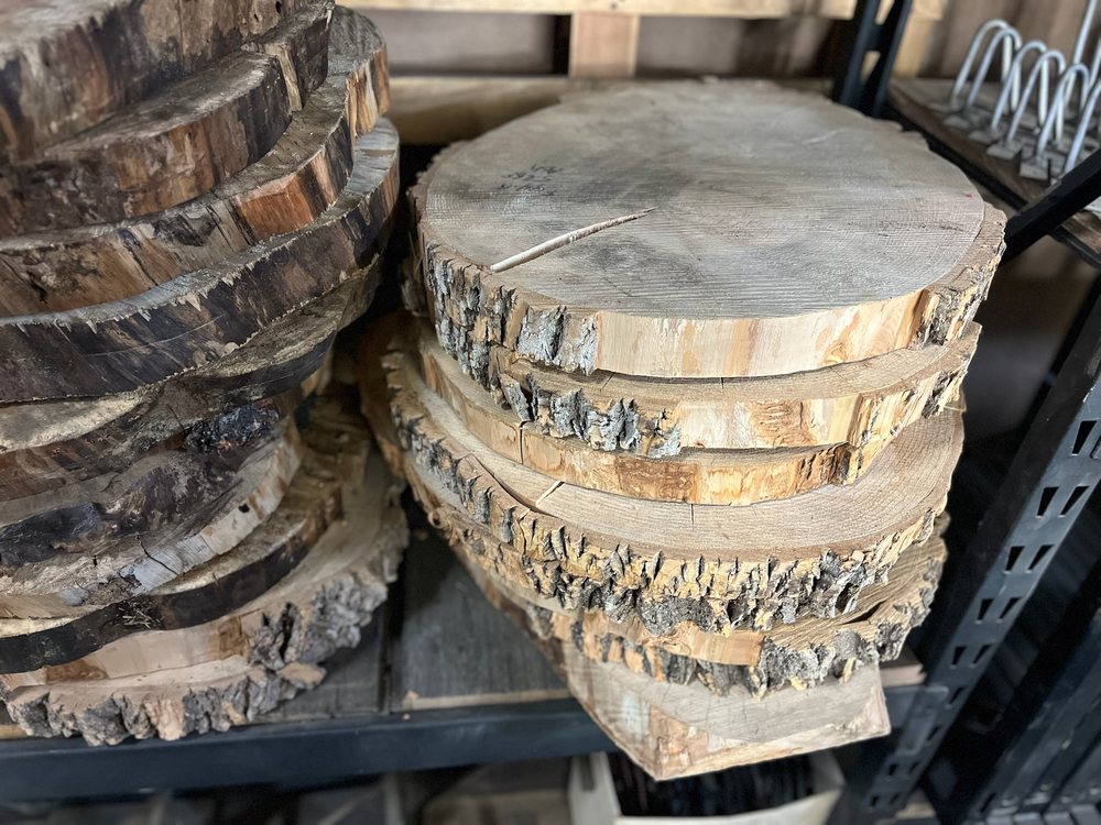 Cottonwood cookies stacked on a rack in the yard, bark edges and end grain showing along the pile