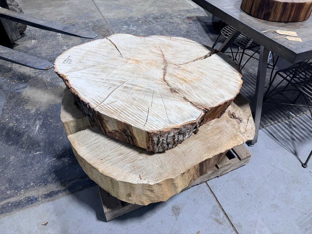 Two cottonwood rounds stacked on a steel table base, the natural bark perimeter visible on both