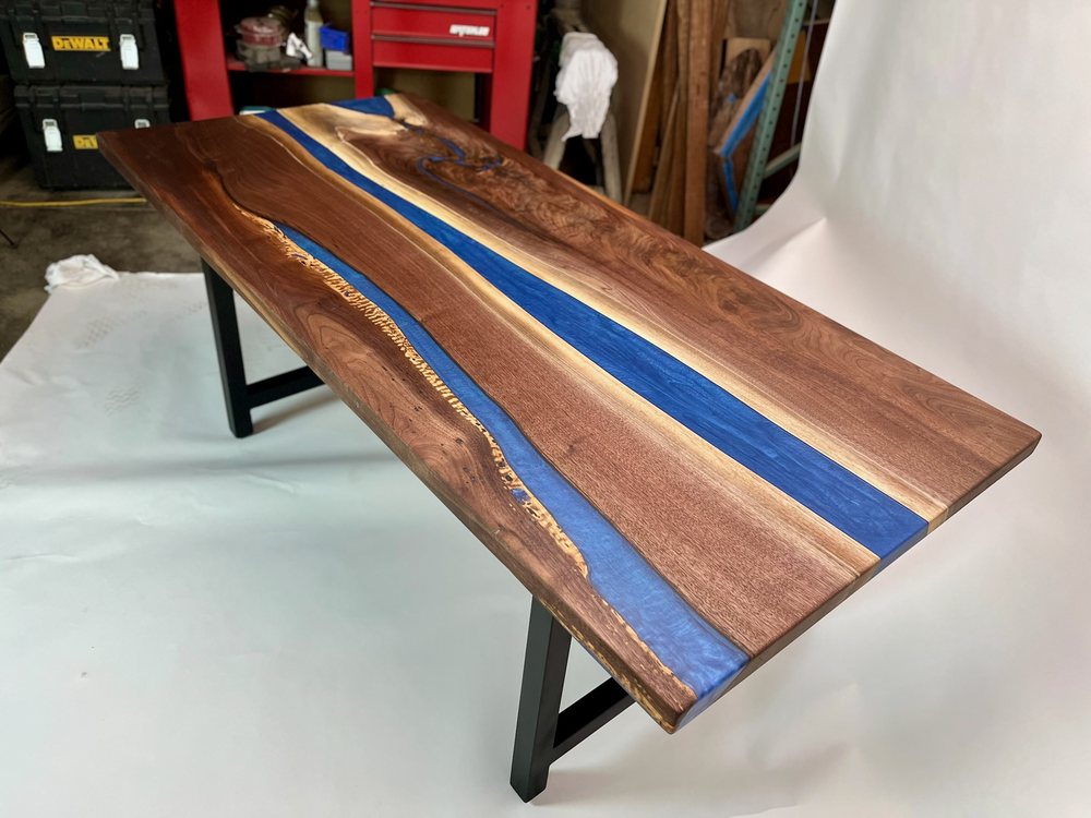 Walnut top with a blue epoxy river on a flat black steel base, finished and ready to go out