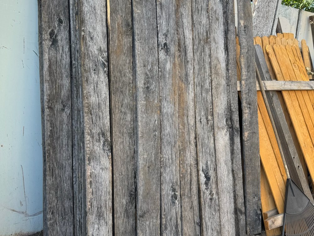 Kentucky horse fence boards stood on end against a wall, weathered grey faces and long vertical grain