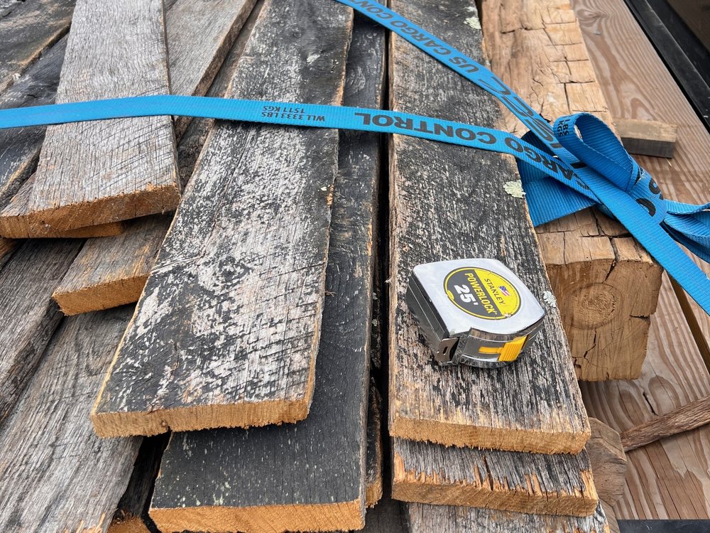 Strapped stack of horse fence boards with a tape measure across them, dark show faces beside tan sawn backs