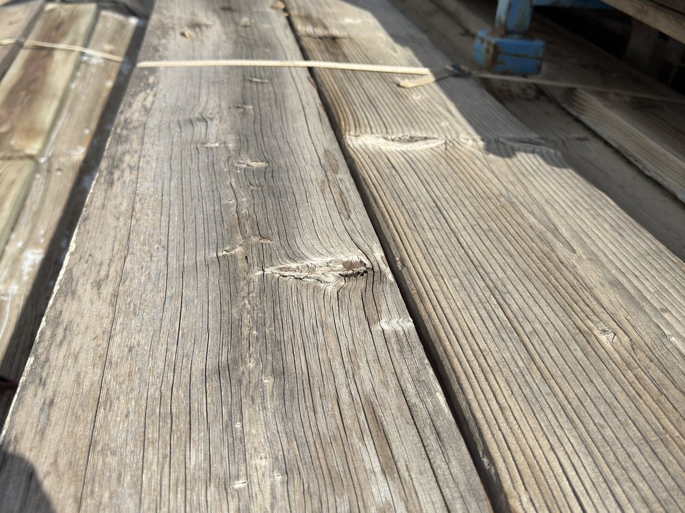 Full length of a speedway bleacher board on the rack, seating face worn smooth end to end